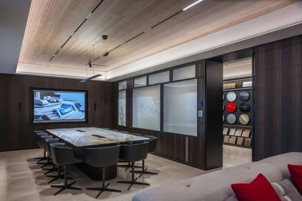Lounge di bordo con divani, finiture in legno e schermo integrato nell'arredo.